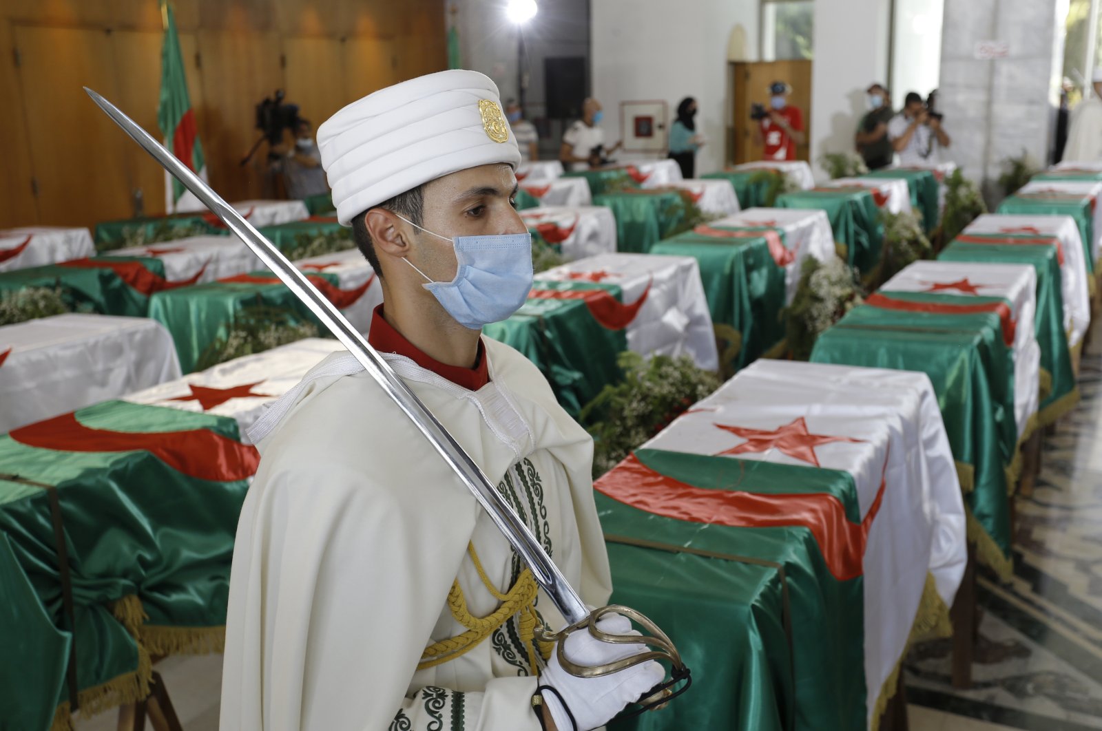 A soldier guards the remains of 24 Algerians at the Moufdi-Zakaria culture palace in Algiers, Friday, July, 3, 2020. (AP Photo)