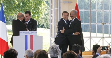 Libyan Prime Minister Fayez Sarraj (L) and French Foreign Minister Jean-Yves Le Drian (2nd from L), and French President Emmanuel Macron (2nd from R) and putschist Gen. Khalifa Haftar (R) hug each other after a news conference at the Chateau of the La Celle-Saint-Cloud, west of Paris, France, July 25, 2017. (AP Photo)