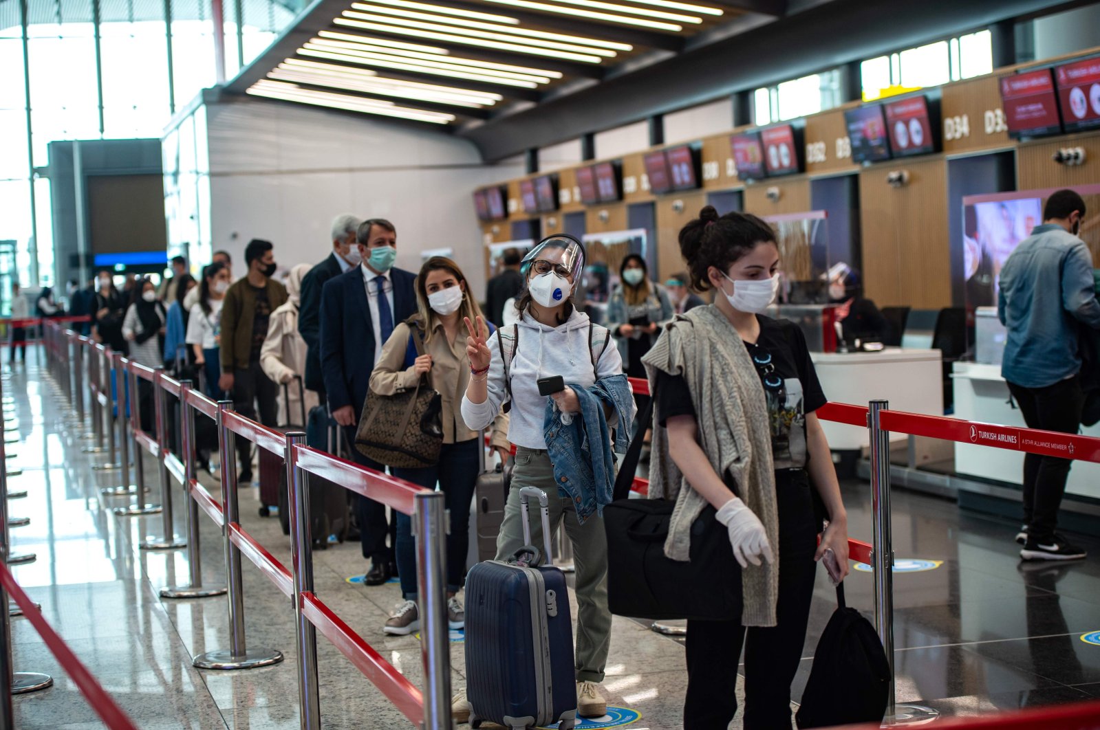 Travelers at the Istanbul Airport wearing protective face masks queue as an employee serves a passenger, Istanbul, Turkey, June 1, 2020. (AFP Photo)