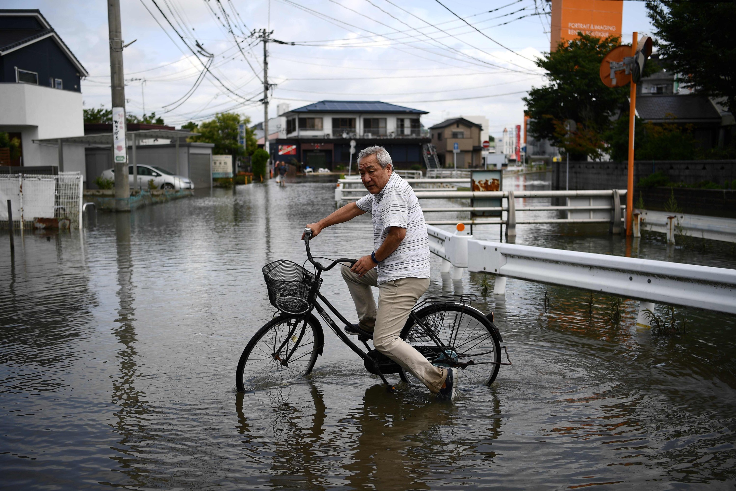 A man cycles through flood waters in Kurume, in Kumamoto Prefecture on July 8, 2020. (AFP Photo)