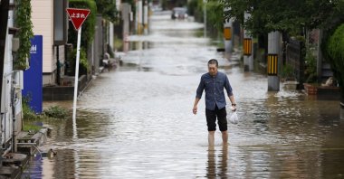 A man walks through a flooded road following heavy rain in Omuta, Fukuoka prefecture, southern Japan Tuesday, July 7, 2020. Floodwaters flowed down streets in southern Japanese towns hit by heavy rains. (Juntaro Yokoyama/Kyodo News via AP)