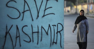 A Kashmiri woman stands next to a graffiti written on a wall during restrictions, Srinagar, Sept. 15, 2019. (REUTERS Photo)