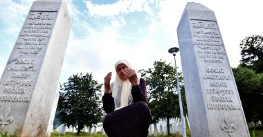 Bosnian Muslim woman Mejra Djogaz, 71, survivor of Srebrenica 1995 massacre, prays between her sons' tombstones, Omer, 19, and Munib, 21, her two sons killed in the massive killing of Srebrenica during Bosnia's 1992-95 war, at Potocari memorial center, near Srebrenica, July 3, 2020. (AFP)