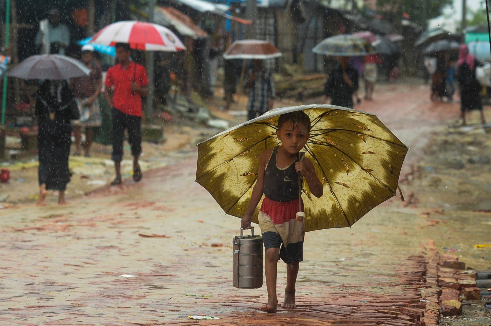 A Rohingya refugee boy shelters under an umbrella as he makes his way during a monsoon rainfall at Kutupalong refugee camp in Ukhia on Sept. 12, 2019. (AFP Photo)