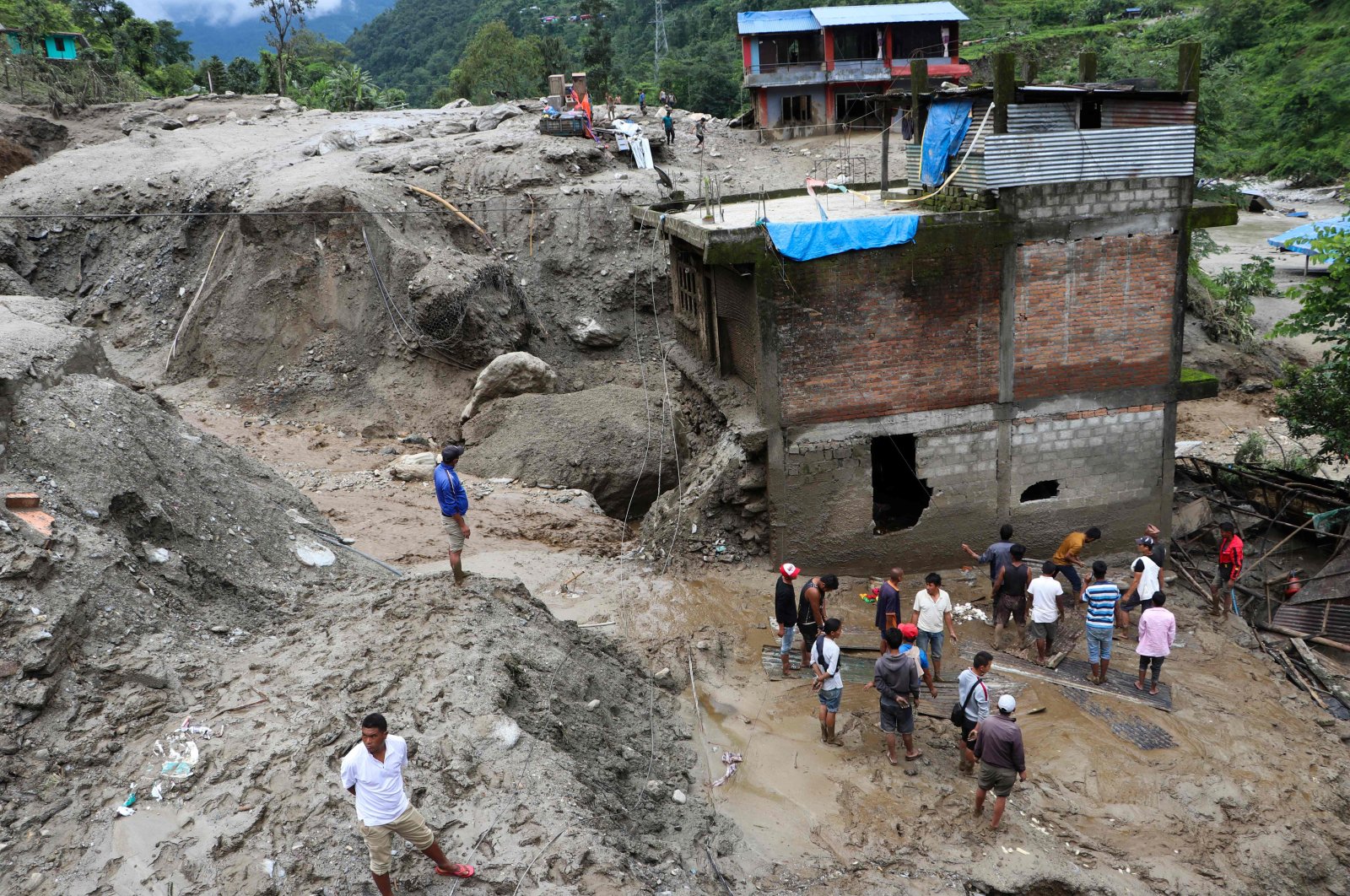 Residents and rescue workers inspect the area outside a house damaged by a landslide and the swell of the Thado-Koshi river due to heavy rains in Jambu village of Sindhupalchok district, some 80 kilometers northeast of Kathmandu, Nepal, July 9, 2020. (AFP Photo)