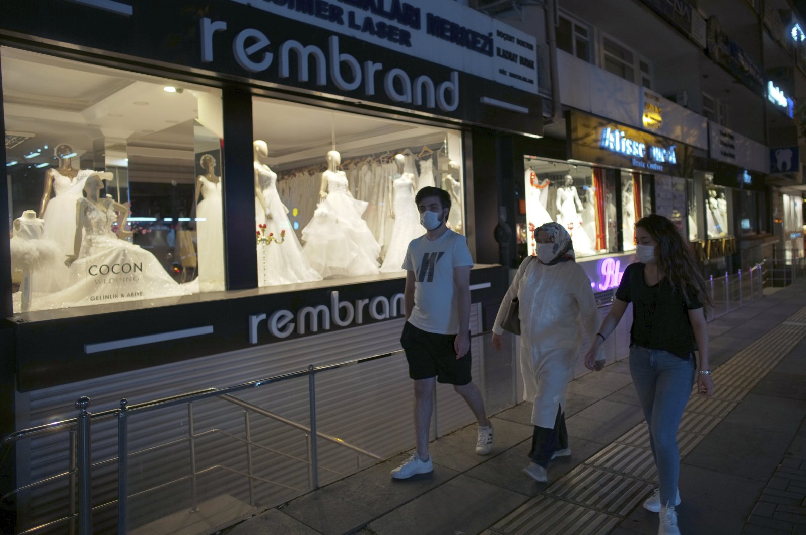People wearing face masks to protect against the spread of coronavirus, walk on a busy street, in Ankara, Turkey, late Wednesday, July 8, 2020. (AP Photo)