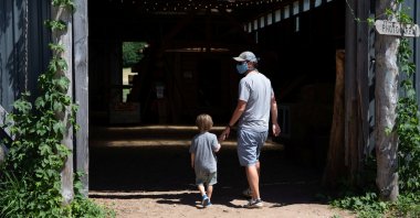 A man wearing a face mask walks with a child around Pond Hill Farm in Harbor Springs, Michigan, U.S. July 11, 2020. (Reuters Photo)
