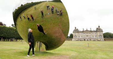 British-Indian artist Anish Kapoor is reflected in one of his sculptures as he poses for photographs in the gardens at Houghton Hall in Norfolk, Britain, July 9, 2020. (REUTERS PHOTO)