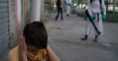 A boy protects his ears as a volunteer sprays disinfectant in an alleyway to help contain the spread of the coronavirus in the Babilonia slum of Rio de Janeiro, Brazil, July 12, 2020. (AP Photo)