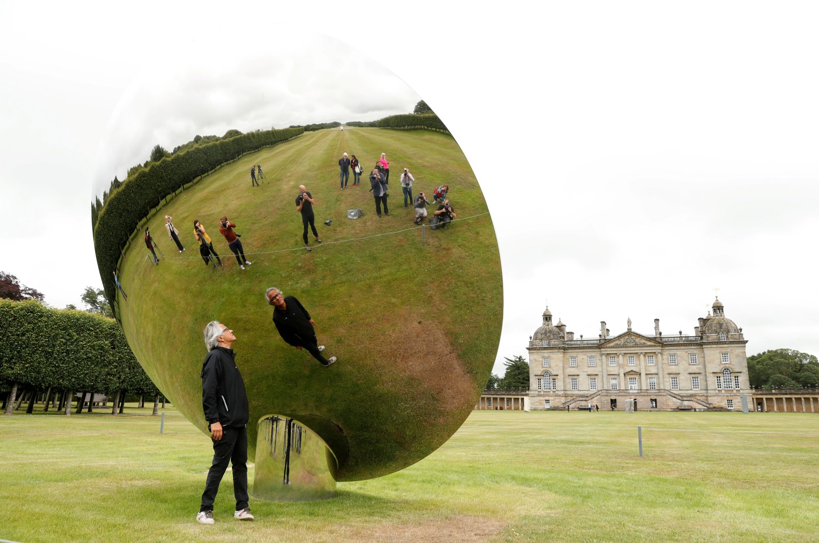 British-Indian artist Anish Kapoor is reflected in one of his sculptures as he poses for photographs in the gardens at Houghton Hall in Norfolk, Britain, July 9, 2020. (REUTERS PHOTO)