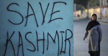 A Kashmiri woman stands next to a graffiti written on a wall during restrictions, Srinagar, Sept. 15, 2019. (REUTERS Photo)