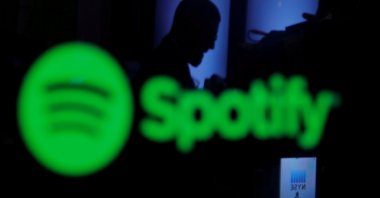 A trader is reflected in a computer screen displaying the Spotify brand before the company begins selling as a direct listing on the floor of the New York Stock Exchange in New York, April 3, 2018. (Reuters Photo)