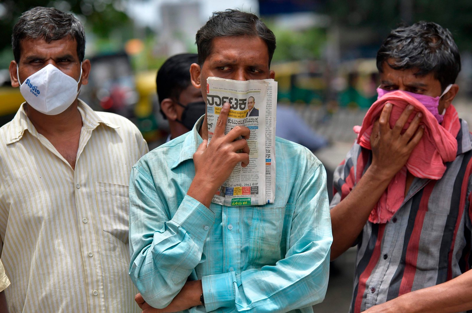 A man holds a newspaper to cover his face in the absence of his face mask during the coronavirus pandemic, in Bangalore, India, July 9, 2020. (AFP Photo)