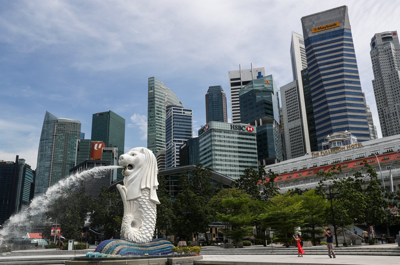 People are dwarfed against the financial skyline as they take photos of the Merlion statue along the Marina Bay area in Singapore, June 30, 2020. (AP Photo)