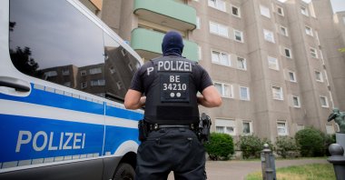 A police officer stands next to a parked police car in front of a building in the Gesundbrunnen district in Berlin, Germany, July 15, 2020. (DPA via AP)