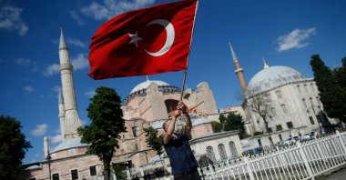 A man waves a Turkish flag outside the Byzantine-era Hagia Sophia, one of Istanbul's main tourist attractions in the historic Sultanahmet district of Istanbul, following Turkey's Council of State's decision, July 10, 2020. (AP)