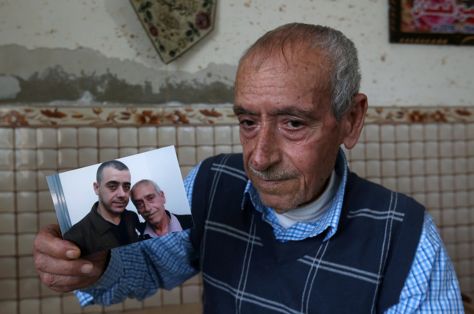 Palestinian man Sameeh Qe'dan, who marks a calendar with a cross to count down the days until his son Abdel-Raouf is released from an Israeli jail, shows a picture of him with Abdel-Raouf, in his home in Rafah in the southern Gaza Strip July 14, 2020. (Reuters Photo)