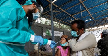 A paramedic wearing protective gear takes a nasal swab from a child, to be tested for the coronavirus, in Karachi, Pakistan, July 13, 2020. (Reuters Photo)
