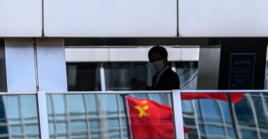 A man walks past a reflection of the Chinese flag (C) on a footbridge in the Central district of Hong Kong on July 16, 2020. (AFP Photo)