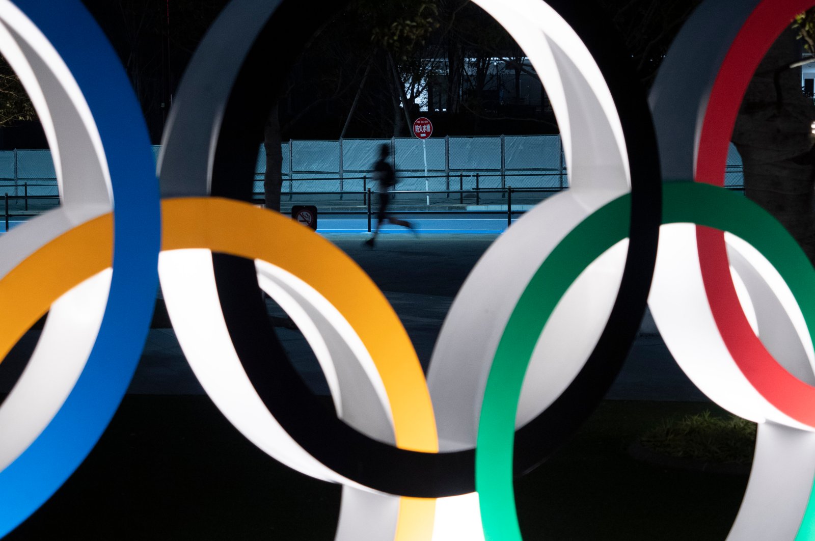 A man jogs past the Olympic rings in Tokyo, Japan, March 30, 2020. (AP Photo)