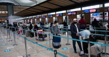 Passengers wearing protective face masks wait to be checked in at Istanbul Airport, June 1, 2020. (AFP Photo)