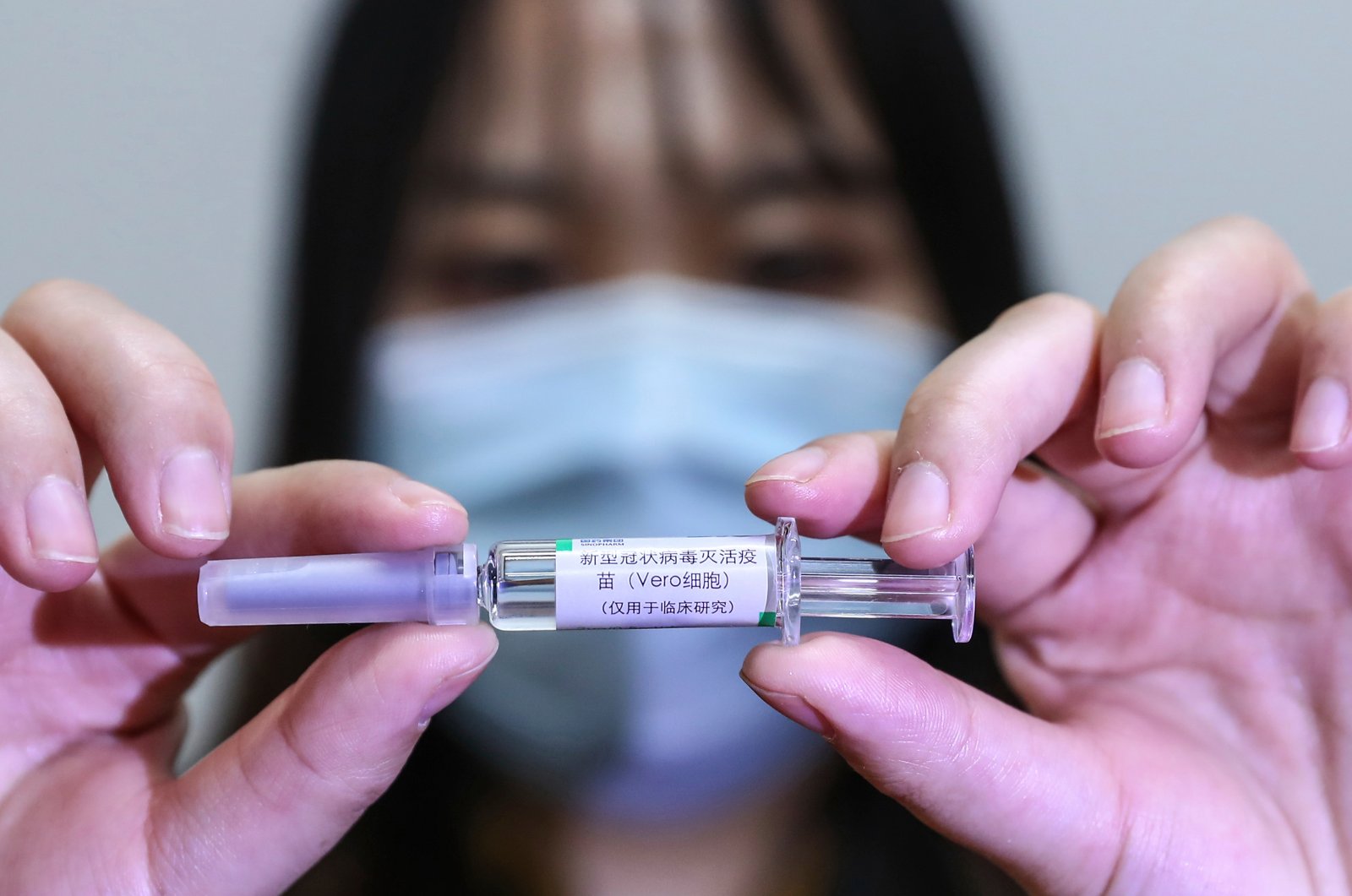 A staff member holds up a sample of a potential COVID-19 vaccine at a production plant of SinoPharm in Beijing, April 10, 2020. (AP Photo)