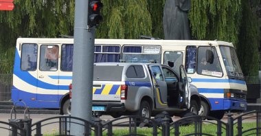 Ukrainian law enforcement officers lie on the ground behind a car near a passenger bus, which was seized by an unidentified person in the city of Lutsk, Ukraine July 21, 2020. (Reuters Photo)