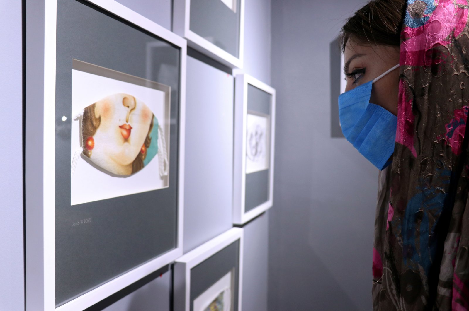 A woman looks at mask-themed artwork on display in an exhibition, following the outbreak of the coronavirus disease, in Tehran, July 18, 2020. (REUTERS)