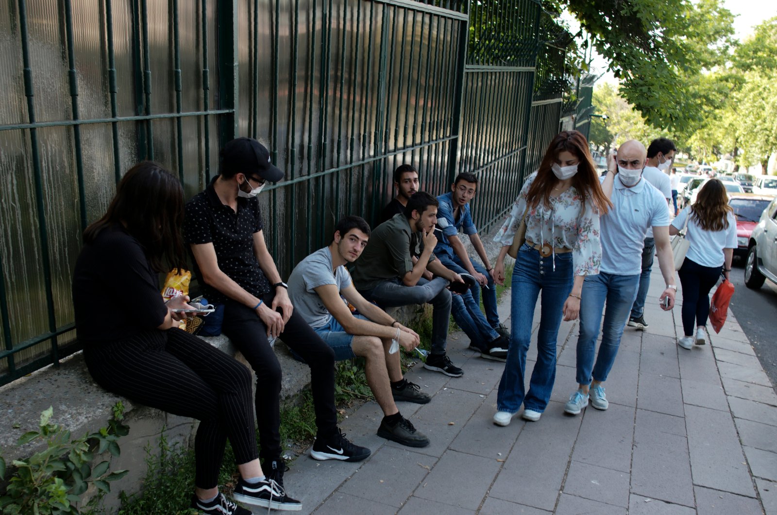 People wearing face masks to protect against the spread of coronavirus, walk past others without face coverings, in Ankara, Monday, June 29, 2020. (AP Photo)