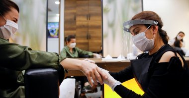 An employee gives manicure to her customer Pınar Ersin, both wearing protective masks in Istanbul, Turkey, May 11, 2020. (REUTERS Photo)