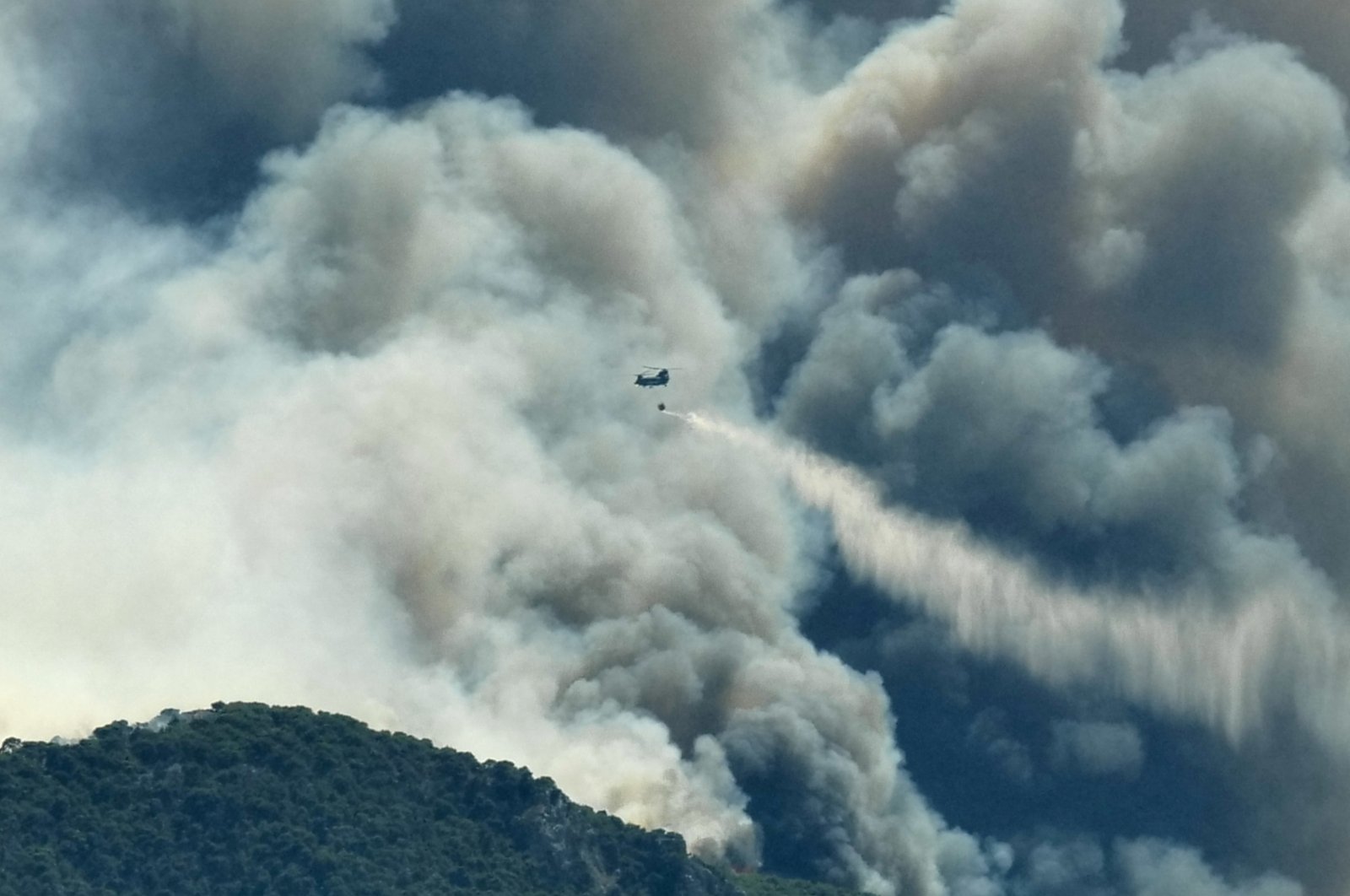 A Chinook helicopter makes a water drop as a wildfire burns near the village of Kechries, Greece, July 22, 2020. (Reuters Photo)