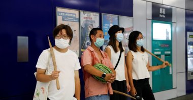 Pro-democracy demonstrators dress in white and hold sticks on their hands to mock an incident that took place one year ago in which an armed crowd wearing white shirts attacked passengers in a train station, during a protest to mark the first anniversary of the attack, demanding justice for the victims of violence and broader freedoms, at a shopping mall in Hong Kong's Yuen Long, China July 21, 2020. (Reuters Photo)