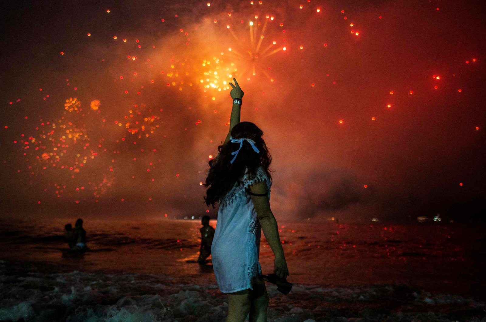 In this file picture taken on December 31, 2019 a woman celebrates as she watches the traditional New Year's fireworks at Copacabana Beach in Rio de Janeiro, Brazil. (AFP Photo)