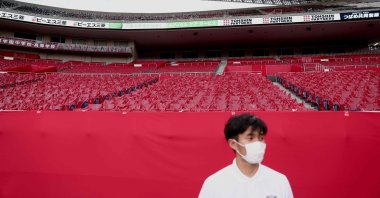 An employee wearing a face mask stands in front of empty seats before the start of the J-League football match between Urawa Reds and Yokohama F. Marinos in Saitama, Japan, July 4, 2020. (AP Photo)