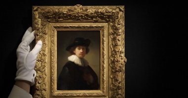 A Sotheby's employee adjusts a painting by Rembrandt Van Rijn called "Self-portrait, wearing a ruff and black hat" at Sotheby's auction rooms in London, Britain, July 23, 2020. (AP Photo)