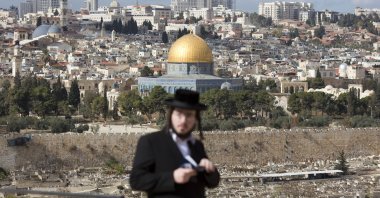 An orthodox Jewish man reads from a holy book in a cemetery near the Dome of the Rock Mosque in the Al Aqsa Mosque compound in Jerusalem's Old City, Thursday, Dec. 7, 2017. (AP Photo)