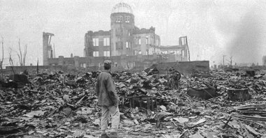 A correspondent stands in a sea of rubble before the shell of a building that once was a movie theater in Hiroshima, Japan, Sept. 8, 1945. (AP Photo)