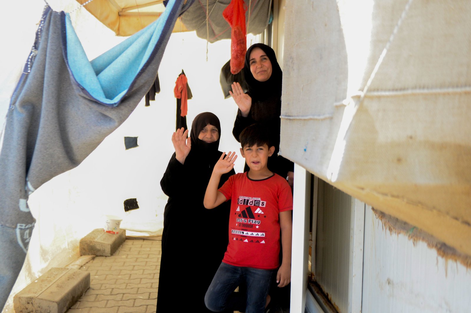 Two women and a boy wave at the door of their house in Elbeyli refugee camp, in Kilis, southern Turkey, July 27, 2020. (AA Photo) 