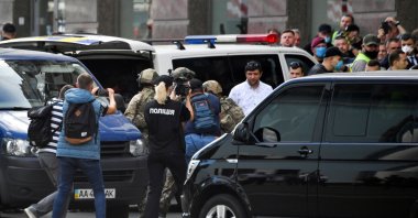 People take pictures as members of Ukrainian special forces escort a man after storming in a bank where a man was taken hostage, Kiev, Ukraine, Aug. 3, 2020. (AFP Photo)
