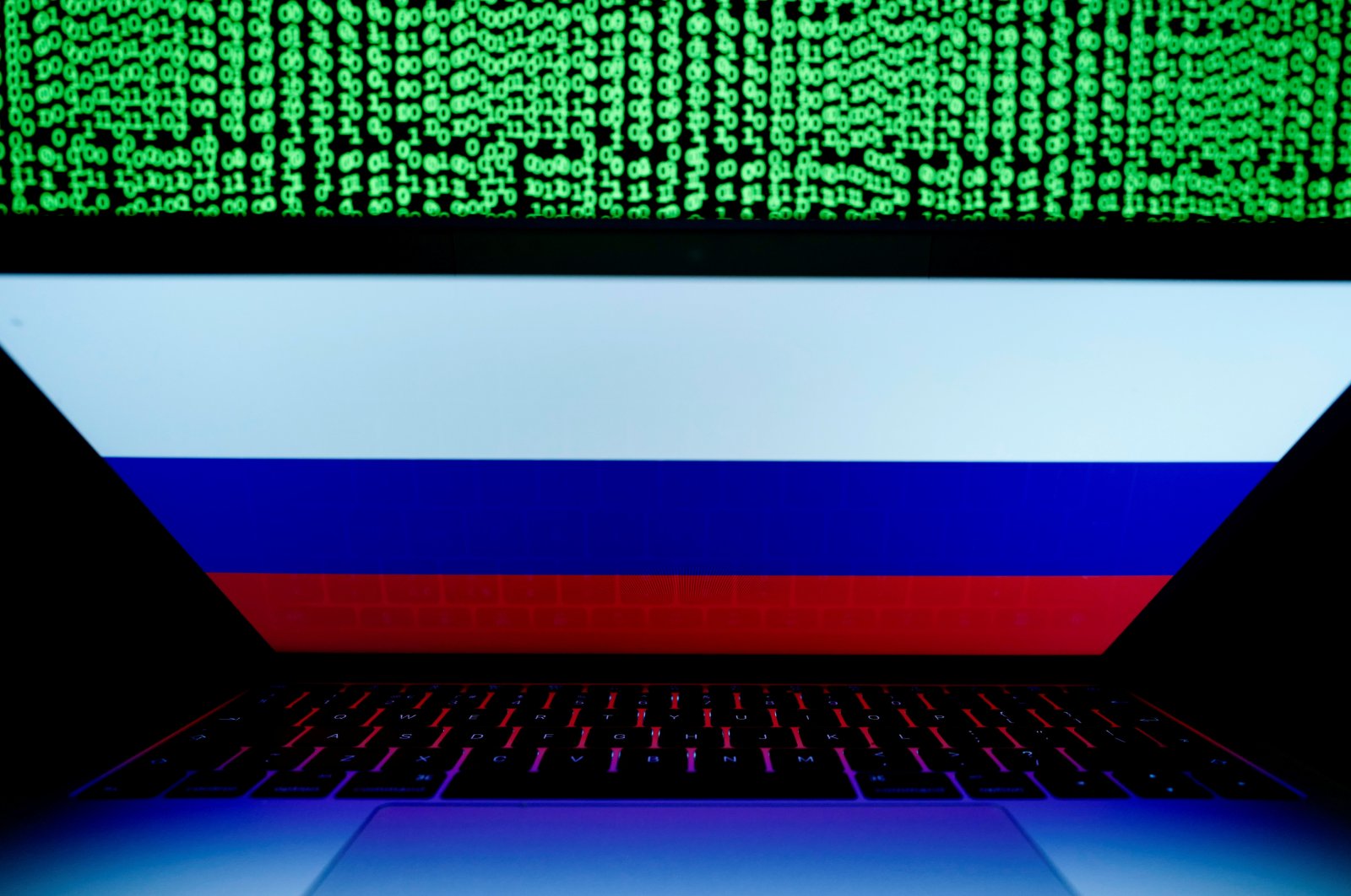 A Russian flag is seen on a laptop screen in front of a computer screen on which cyber code is displayed, in this illustration picture taken March 2, 2018. (Reuters Photo)