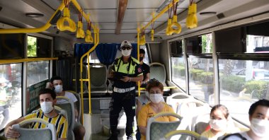 A police officer inspects coronavirus measures in a bus, in Adana, southern Turkey, Aug. 4, 2020. (DHA Photo)
