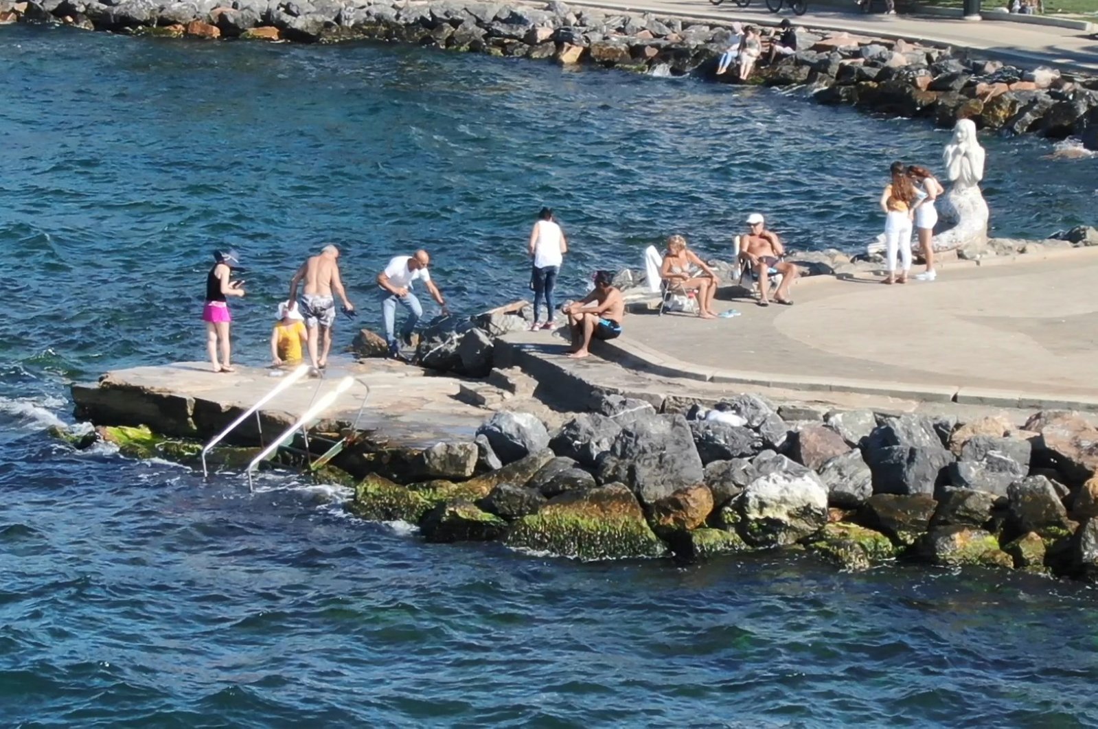 Locals who do not want to pay for private beaches swim off rocky shores in Büyükada, Istanbul, Aug. 3, 2020. (DHA Photo)