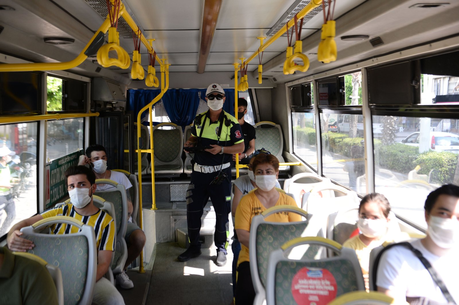 A police officer inspects coronavirus measures in a bus, in Adana, southern Turkey, Aug. 4, 2020. (DHA Photo)