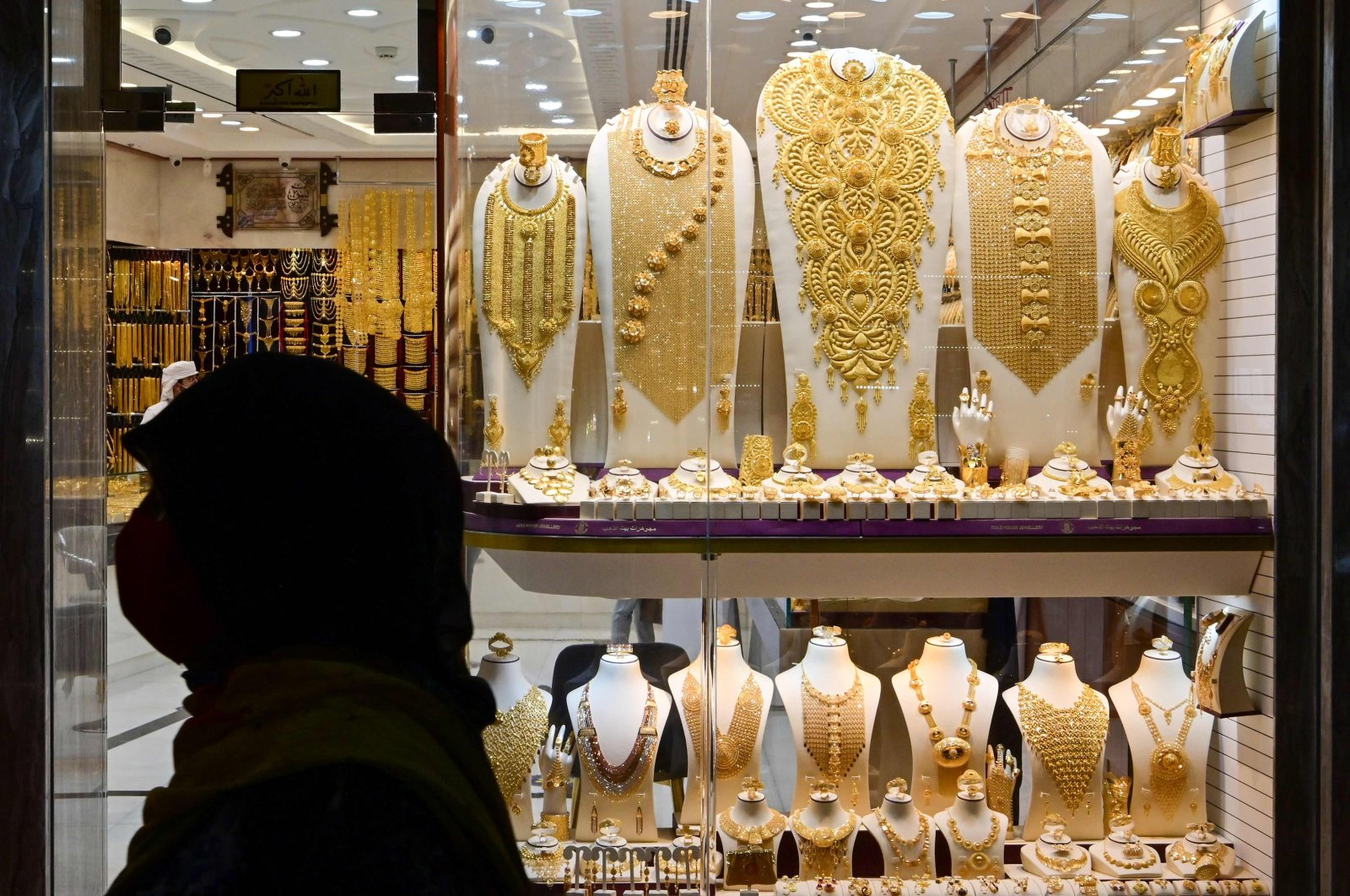 A woman walks past a gold merchant in Dubai Gold Souk in the Gulf emirate, July 29, 2020. (AFP)