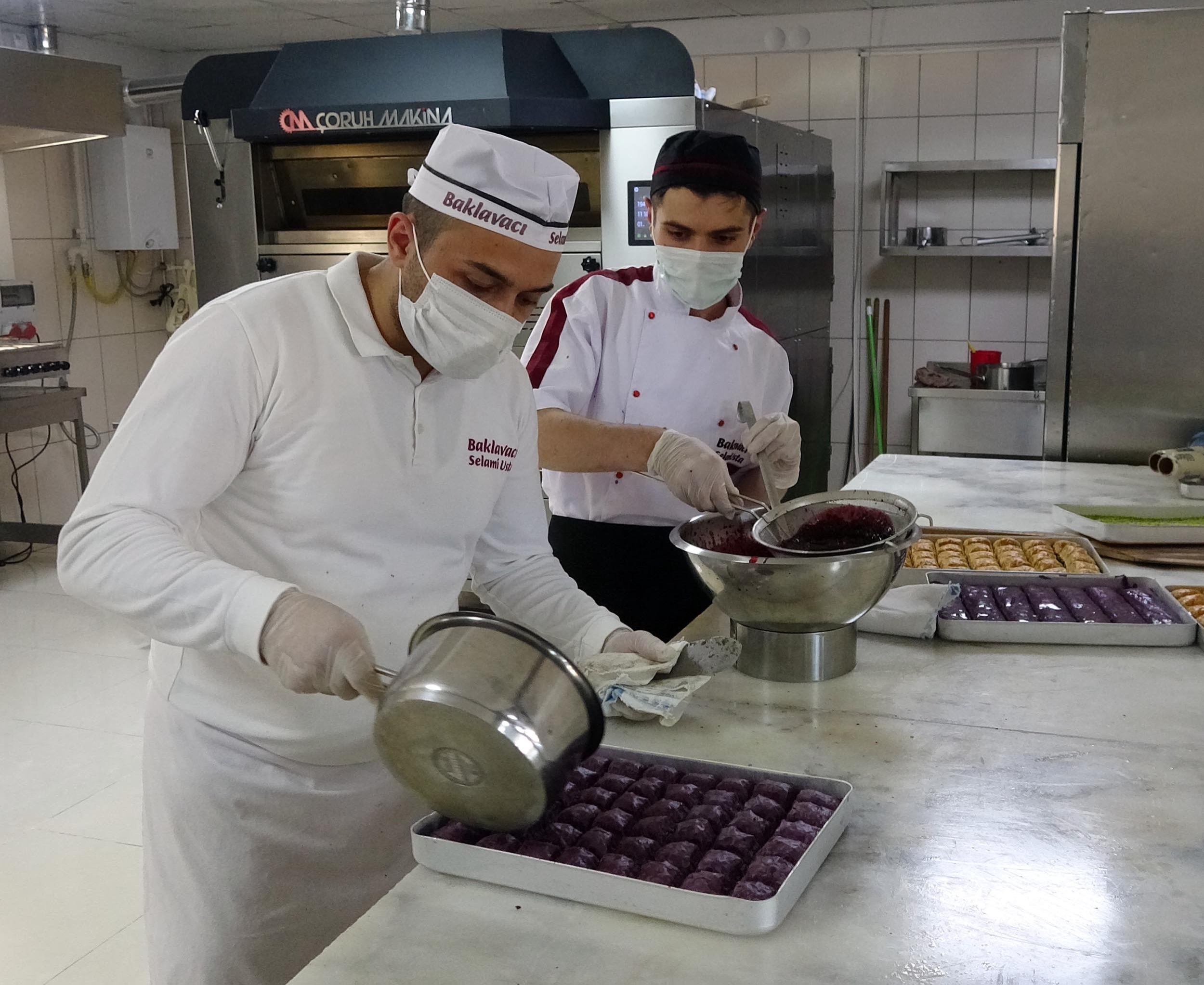Baker Selami Atiş pours his special fruit syrup over a tray of purple baklava in Erzurum, Turkey, Aug 3, 2020. (DHA Photo)