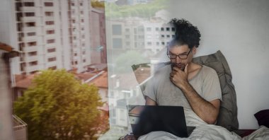 A teacher-researcher works in his bed on his computer in France, on April 18, 2020. (via Reuters)