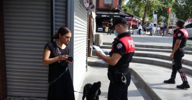 A police officer issues a fine to a woman not wearing a mask in the Beşiktaş district of Istanbul, Turkey, Aug. 6, 2020. (DHA Photo)