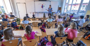 Teacher Francie Keller welcomes his pupils to the Lankow primary school on the first day of school in Schwerin, Germany, Aug. 3, 2020. (AP Photo)