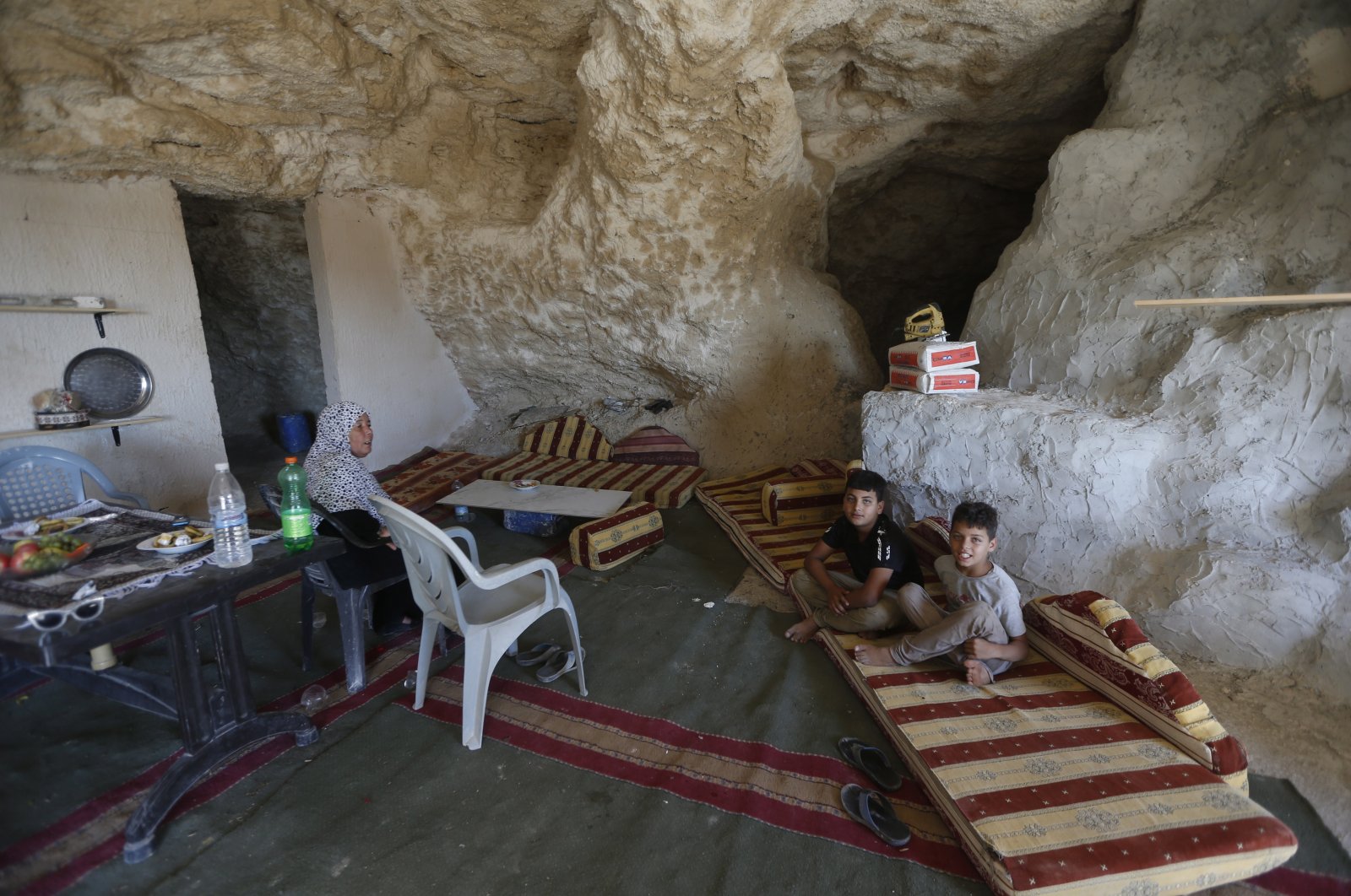Members of a Palestinian family sit inside a cave they use as their home on the outskirts of the West Bank City of Jenin, Palestine, Aug. 1, 2020. (EPA Photo)