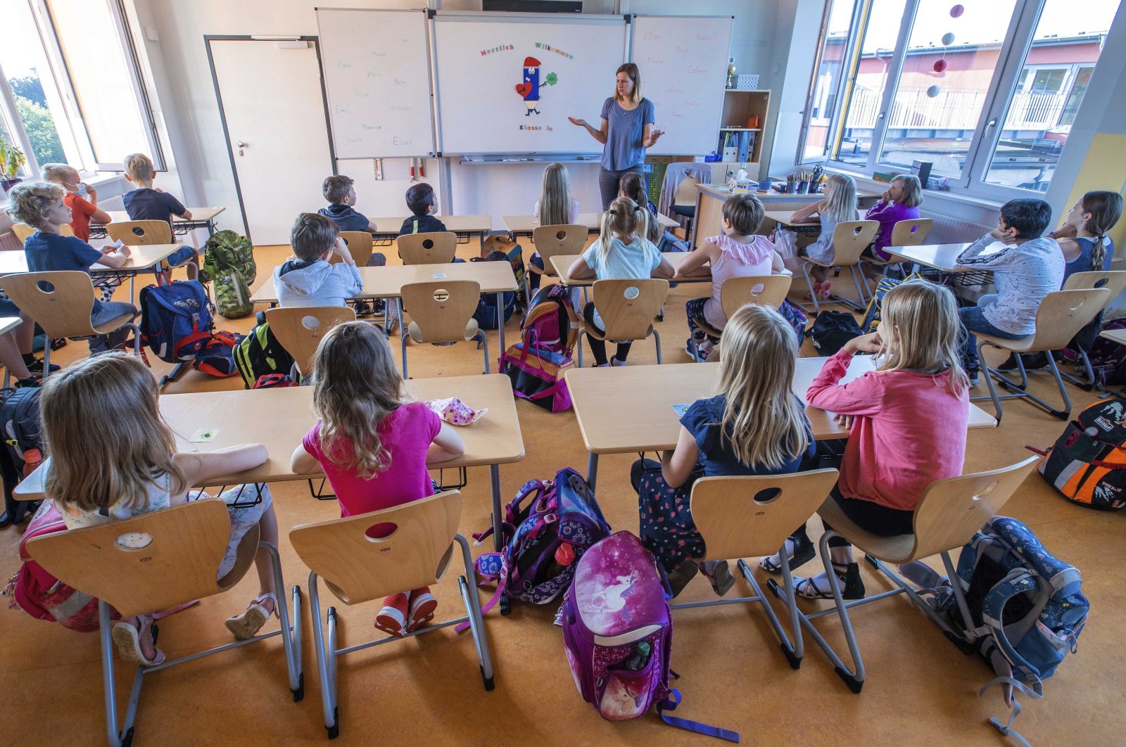 Teacher Francie Keller welcomes his pupils to the Lankow primary school on the first day of school in Schwerin, Germany, Aug. 3, 2020. (AP Photo)